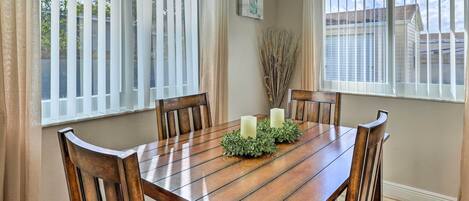 A dining table with four wooden chairs, two candles, and a centerpiece.