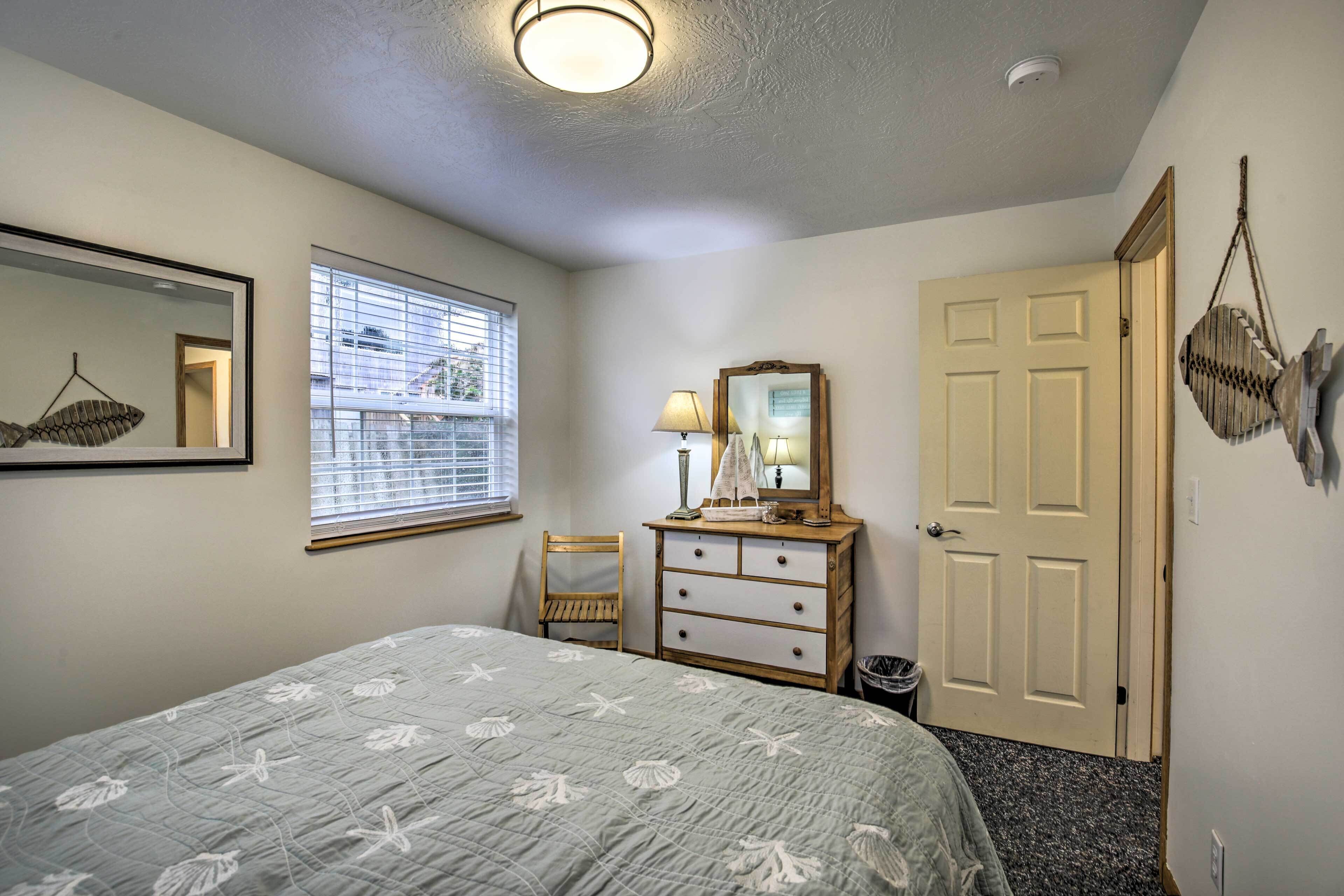 Un dormitorio con cama, cómoda, espejo, ventana y puerta.