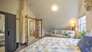 A bedroom with a bed, a sofa, a lamp, and a view of the outdoors. - Logan Road Lookout, Lincoln City Home w/ Game Room (Lincoln City)