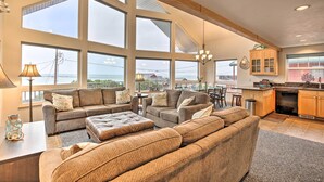 A spacious living room with large windows, a kitchen area, and a dining space. - Logan Road Lookout, Lincoln City Home w/ Game Room (Lincoln City)