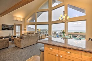 A spacious living area with a large window overlooking a balcony, a kitchen with granite countertops, and a cozy seating area with a sofa and armchairs.