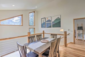 A dining area with a wooden table and chairs, a wooden railing, and a view of the outdoors through large windows. - Creekside Mtn House w/ Deck: 8 Mi to Idaho Springs (Dumont)