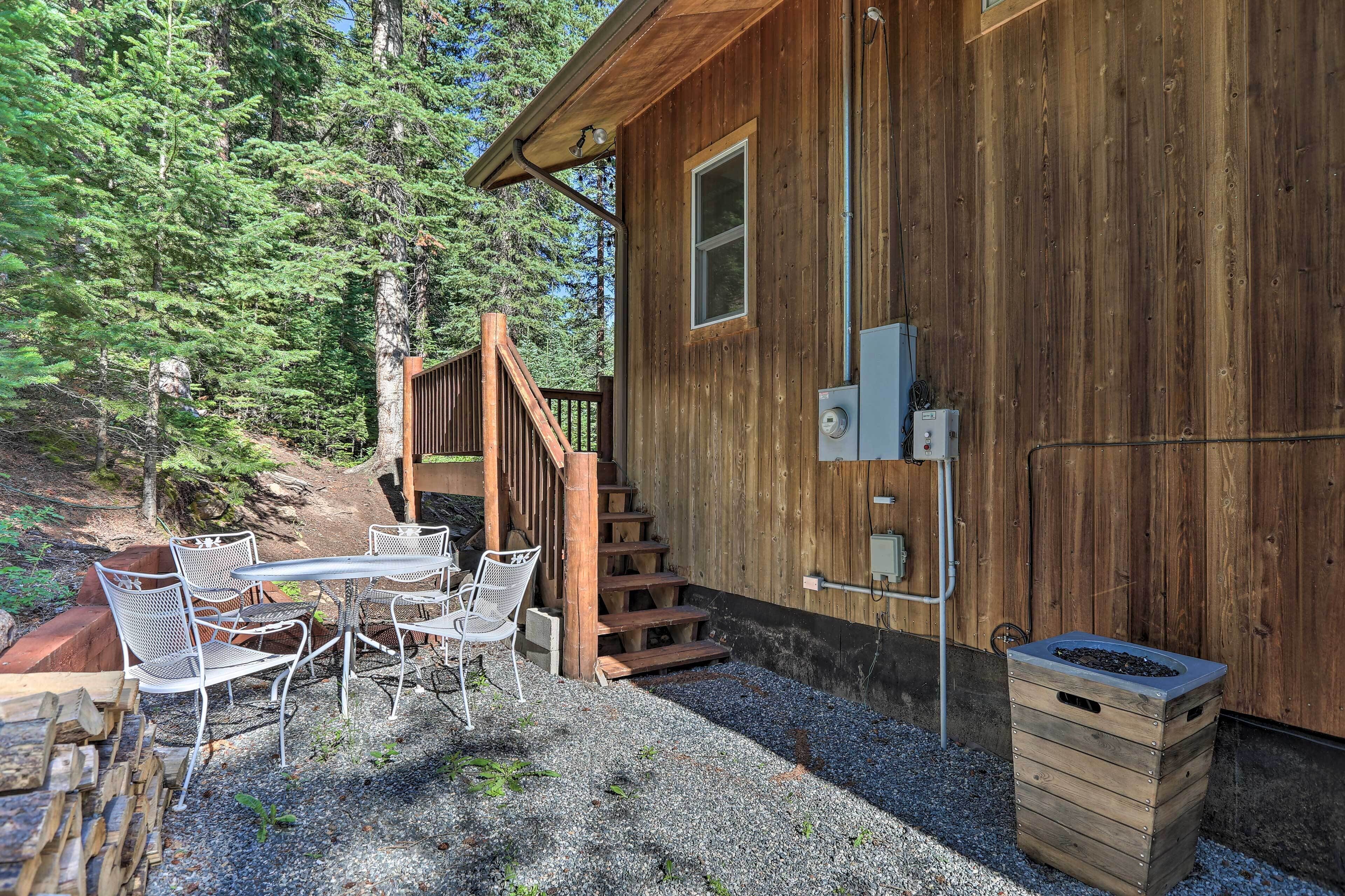 A wooden cabin with a gravel patio, outdoor seating, and a staircase leading to a deck.