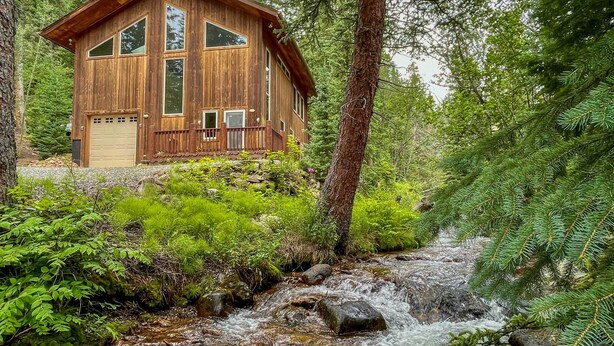 A wooden cabin with a garage, surrounded by dense forest and a stream. - Creekside Mtn House w/ Deck: 8 Mi to Idaho Springs (Dumont)