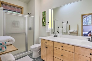 A modern bathroom with a glass shower enclosure, a white toilet, and a wooden vanity with a large mirror. - Creekside Mtn House w/ Deck: 8 Mi to Idaho Springs (Dumont)