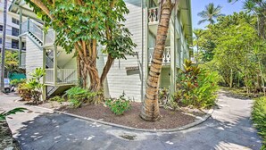 A multi-story building with a staircase leading to the upper floors, surrounded by lush greenery and palm trees. - Kailua-kona Islander Studio: Lanai, Community Pool (Kailua-Kona)