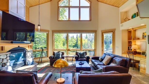 A spacious living room with a fireplace, leather sofas, and large windows offering a view of the outdoors. - Mountain Home ~ 5 Mi to Winter Park Resort! (Winter Park)