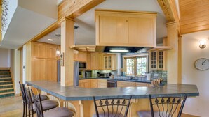 A spacious kitchen with wooden cabinets, a large island with bar stools, and a visible clock on the wall. - Mountain Home ~ 5 Mi to Winter Park Resort! (Winter Park)