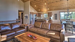 A spacious living area with a brown leather sofa, wooden coffee table, and a kitchen in the background. - Fairplay Dream Escape: 27 Miles to Breckenridge! (Fairplay)