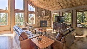 A spacious living room with a stone fireplace, leather sofas, a wooden coffee table, and a television. - Fairplay Dream Escape: 27 Miles to Breckenridge! (Fairplay)