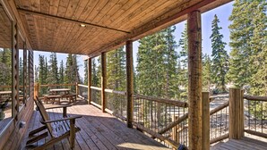 A wooden deck with picnic tables and benches, surrounded by tall trees. - Fairplay Dream Escape: 27 Miles to Breckenridge! (Fairplay)