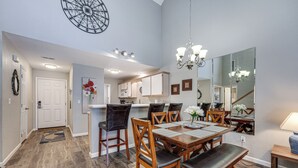 A spacious dining area with a wooden table and chairs, a chandelier, and a large mirror reflecting the room. - Lakefront Branson Penthouse w/ Resort Amenities! (Branson)