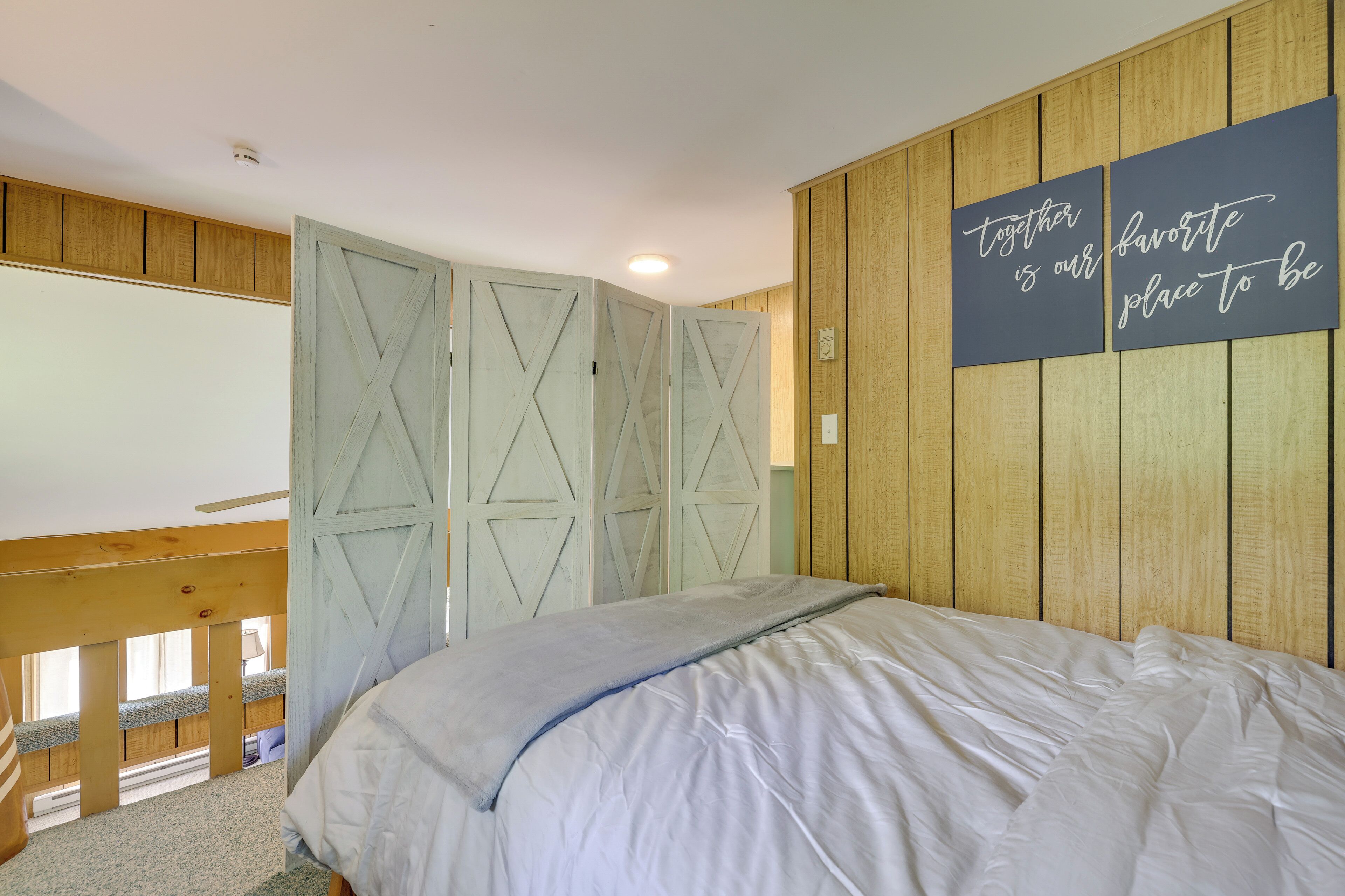 A bedroom with a bed, a wooden wardrobe, and a wall with a motivational quote.