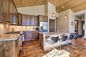 A modern kitchen with wooden cabinets, stainless steel appliances, and a central island with bar stools.