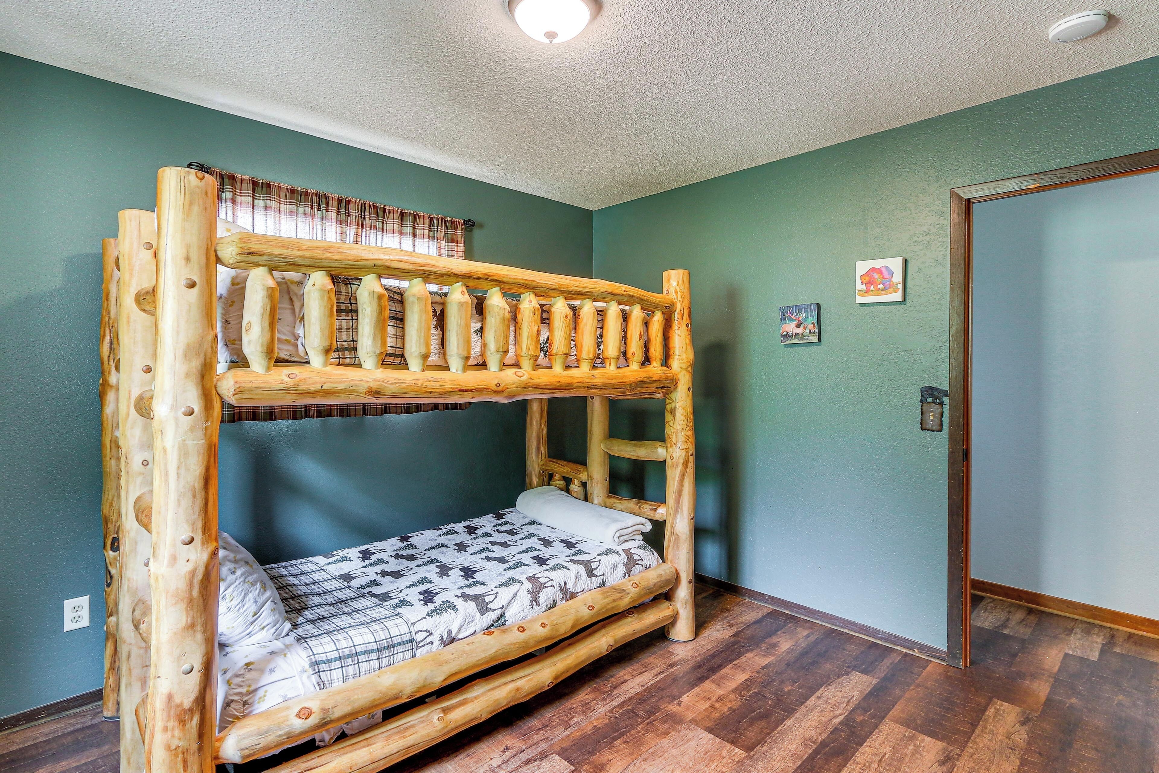 A bunk bed with a wooden frame, a window with a plaid curtain, and a door with a lock.