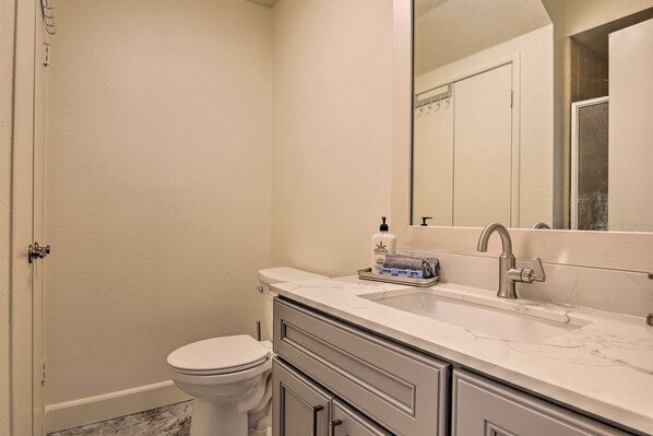 A bathroom with a toilet, a sink, a mirror, and a bottle of HEMPZ soap.