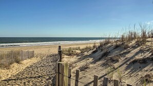 Ein Sandstrand mit einer Holzlattenzaun und Dünen.