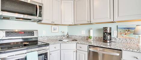 A kitchen with white cabinets, a microwave, stove, oven, and dishwasher.