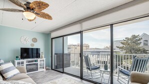 Ein geräumiger Balkon mit Deckenventilator, einem Flachbildfernseher und einer Sitzecke mit einem Sessel und einem kleinen Tisch.