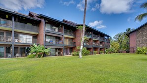A multi-story hotel with balconies, a well-maintained lawn, and tropical landscaping. - Breezy Kaunakakai Retreat w/ Community Pool! (Kaunakakai)