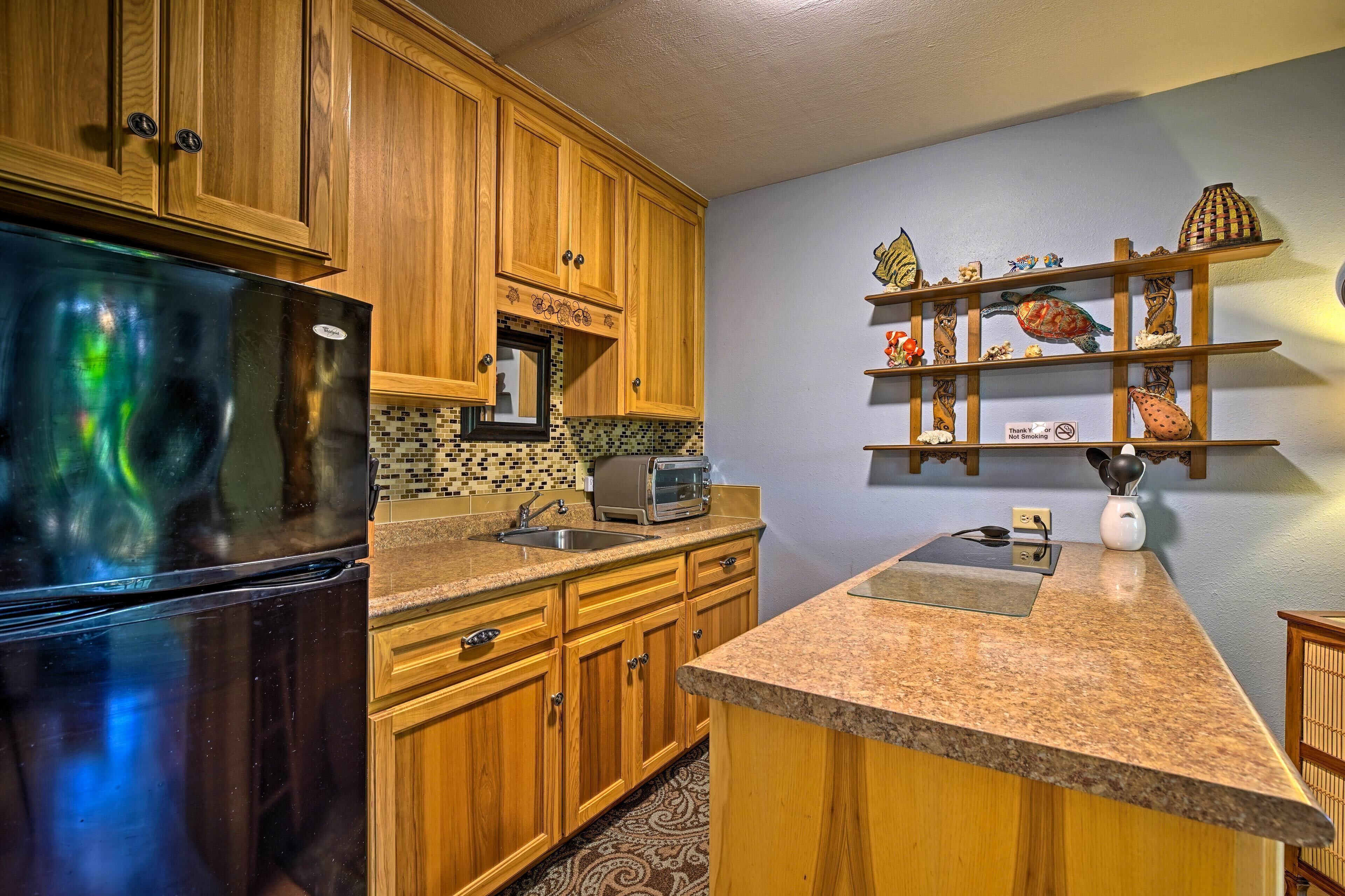 A kitchen with wooden cabinets, a black refrigerator, a microwave, and a shelf with decorative items.