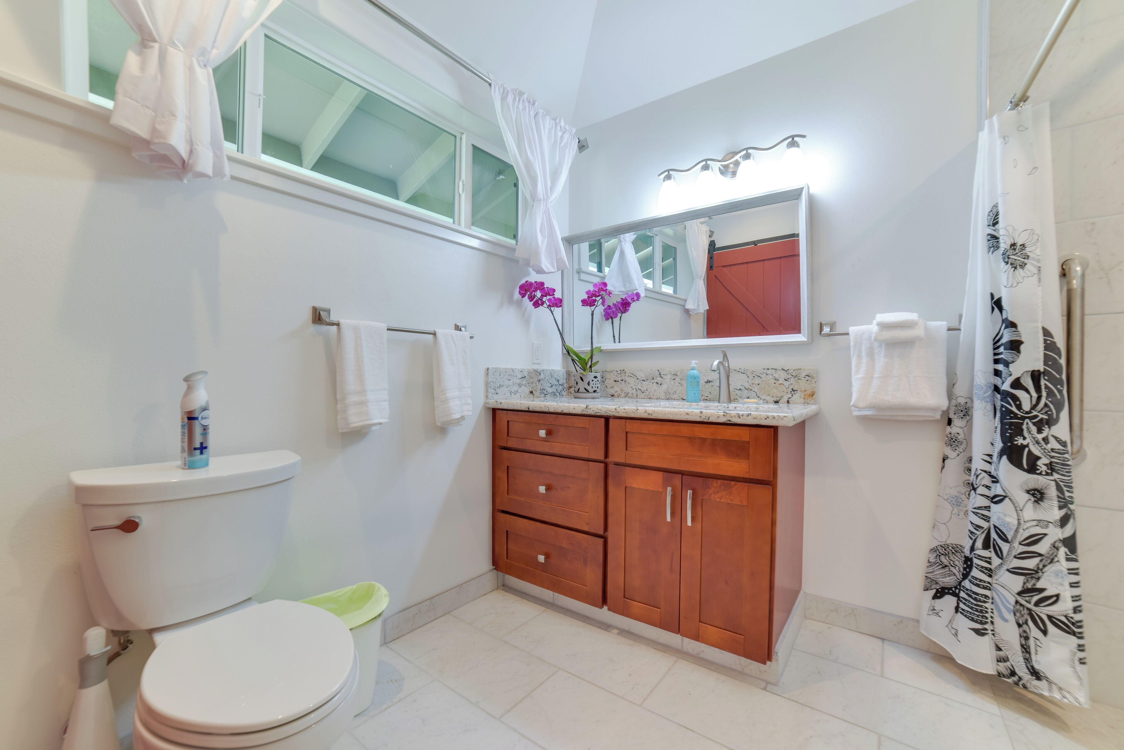 Un bagno con toilette, lavandino, specchio e tenda doccia.
