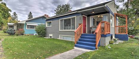 A two-story house with a blue exterior, a red door, and a wooden staircase leading to the front porch.
