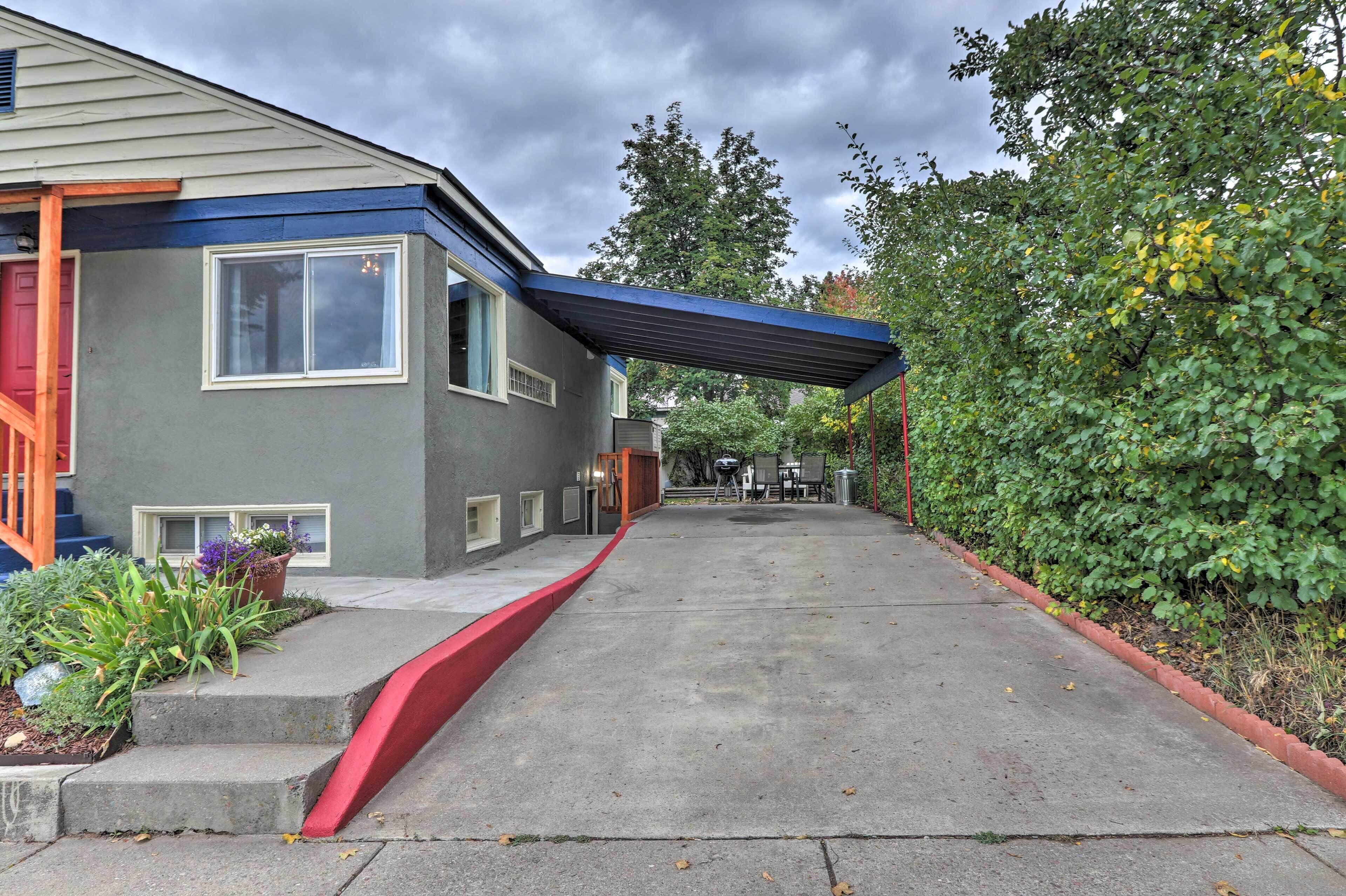 A house with a covered porch, a red front door, and a concrete driveway.