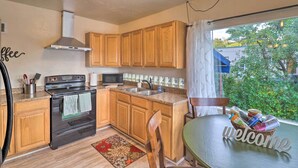 A kitchen with wooden cabinets, a stove, a microwave, and a sink. There is a welcome sign on the table. - Comfy & Cozy Kalispell Home: Walk to Downtown (Kalispell)