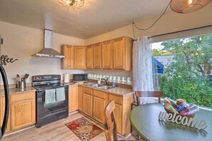A kitchen with wooden cabinets, a stove, a microwave, and a sink. There is a welcome sign on the table.