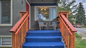 A wooden staircase with blue steps leading to a porch area with two Adirondack chairs and a chandelier. - Comfy & Cozy Kalispell Home: Walk to Downtown (Kalispell)