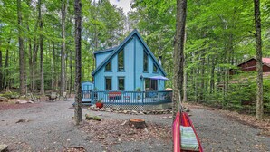 Une cabane bleue avec une véranda et un hamac devant.