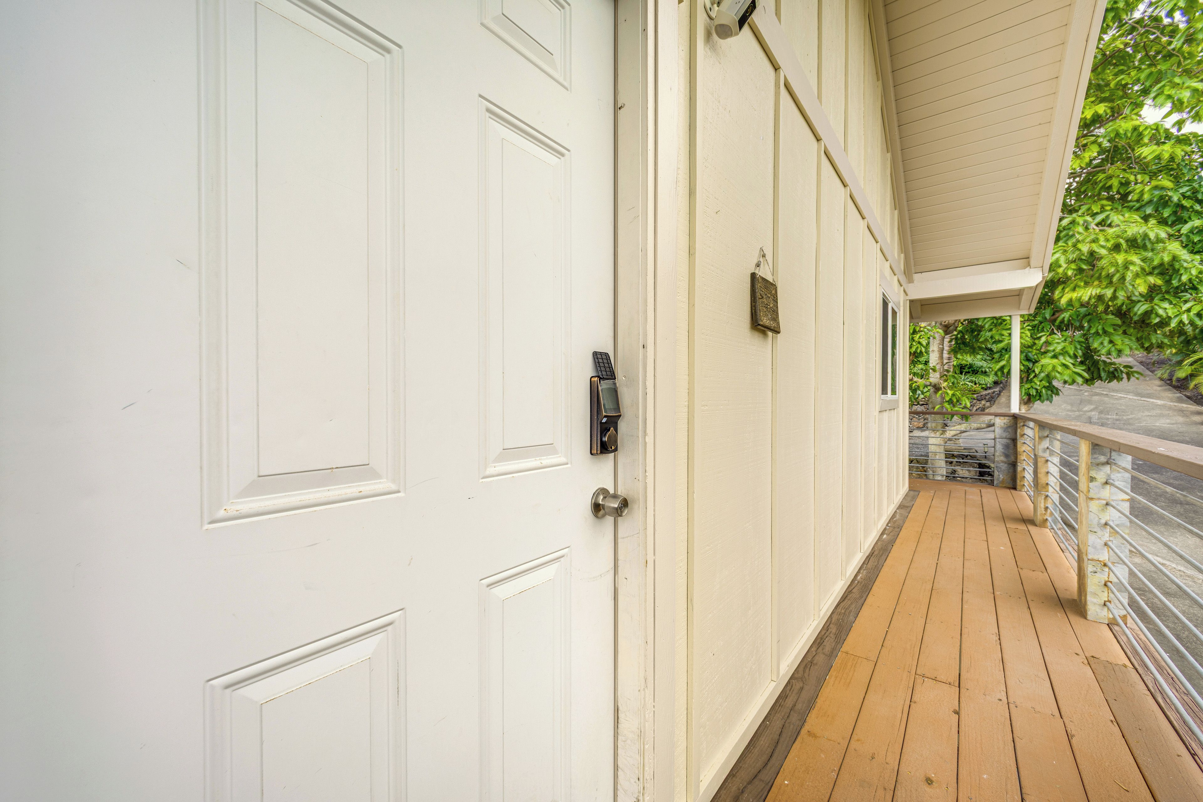A white exterior of a building with a wooden deck and a metal railing.