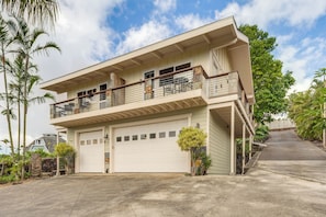 Uma casa de dois andares com garagem, varanda e entrada para carros.