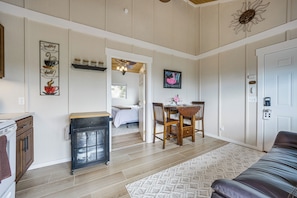 A room with a bed, a dining table with chairs, a kitchen area, and a door. - Cozy Kona Coast Apt w/ Lanai ~ 8 Miles to Beach! (Kailua-Kona)