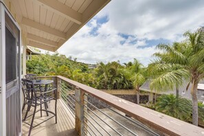 A balcony with a table and chairs, overlooking a lush garden with palm trees and a clear sky. - Cozy Kona Coast Apt w/ Lanai ~ 8 Miles to Beach! (Kailua-Kona)