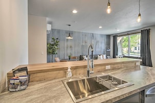 Una cocina moderna con pileta de acero inoxidable, encimera de madera e iluminación colgante.