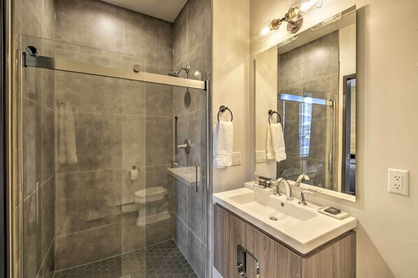 A modern bathroom with a glass-enclosed shower, a white sink, and a large mirror.