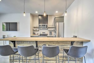 Una cocina moderna con una isla grande, electrodomésticos de acero inoxidable y un televisor de pantalla plana montado en la pared.