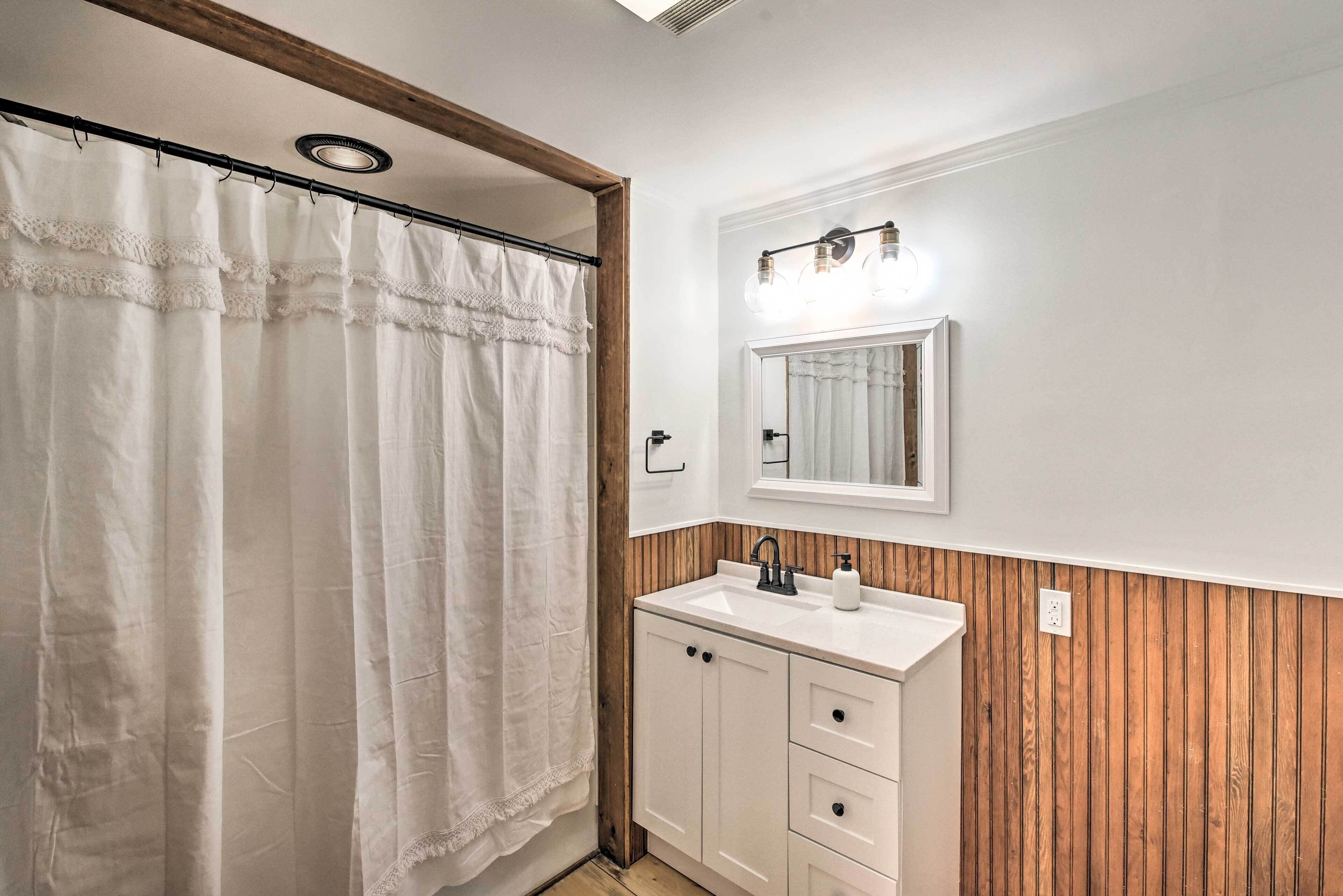 Une salle de bain avec un mur recouvert de panneaux en bois, un lavabo blanc et un miroir au-dessus.