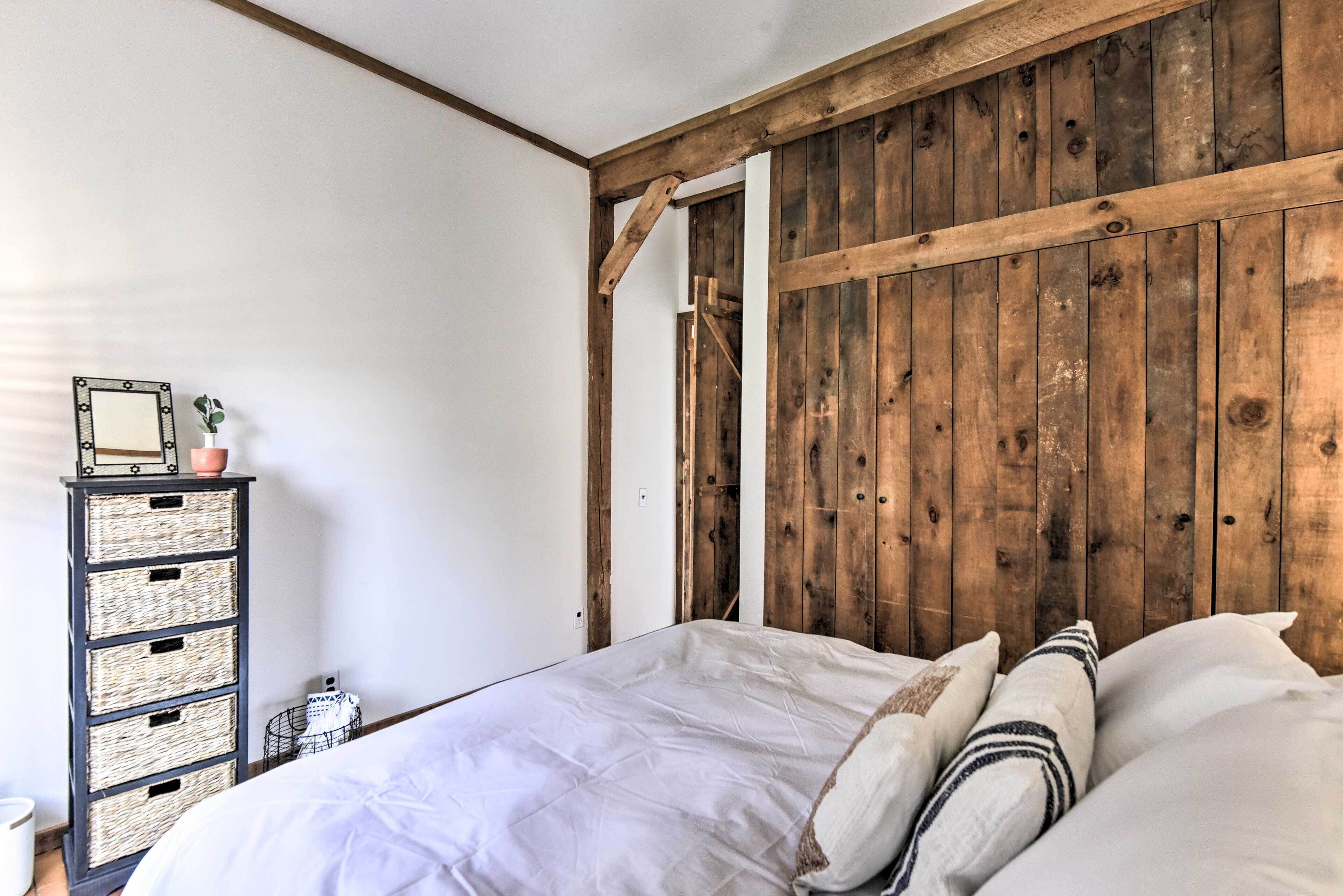 A bedroom with a wooden headboard, a bed with white bedding, and a side table with a mirror and decorative items.
