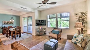 A spacious living area with a dining table, sofa, and TV. - Kona Coast Condo w/ Lanai & Outdoor Kitchen! (Kamuela)