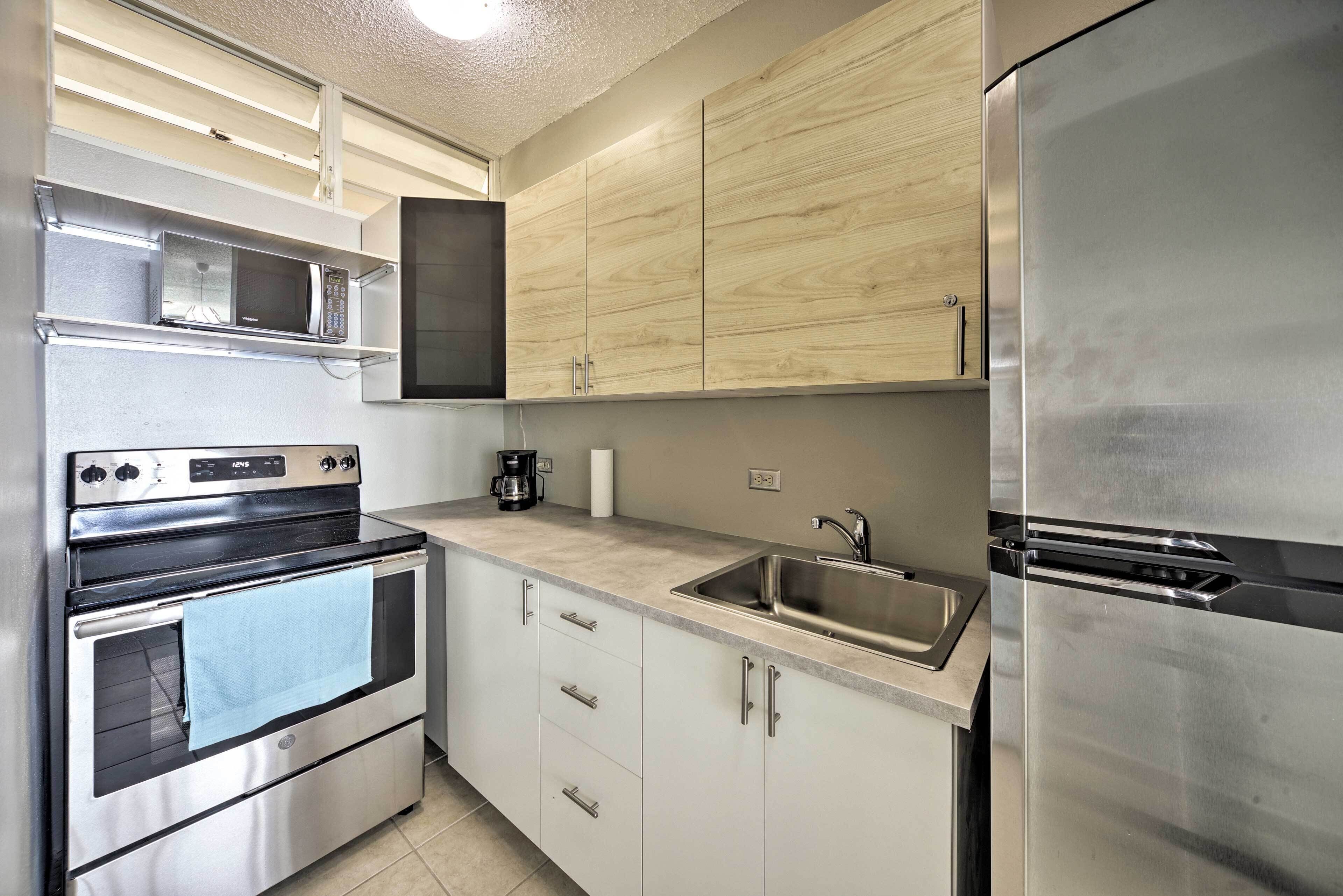 A modern kitchen with stainless steel appliances, wooden cabinets, and a built-in microwave.