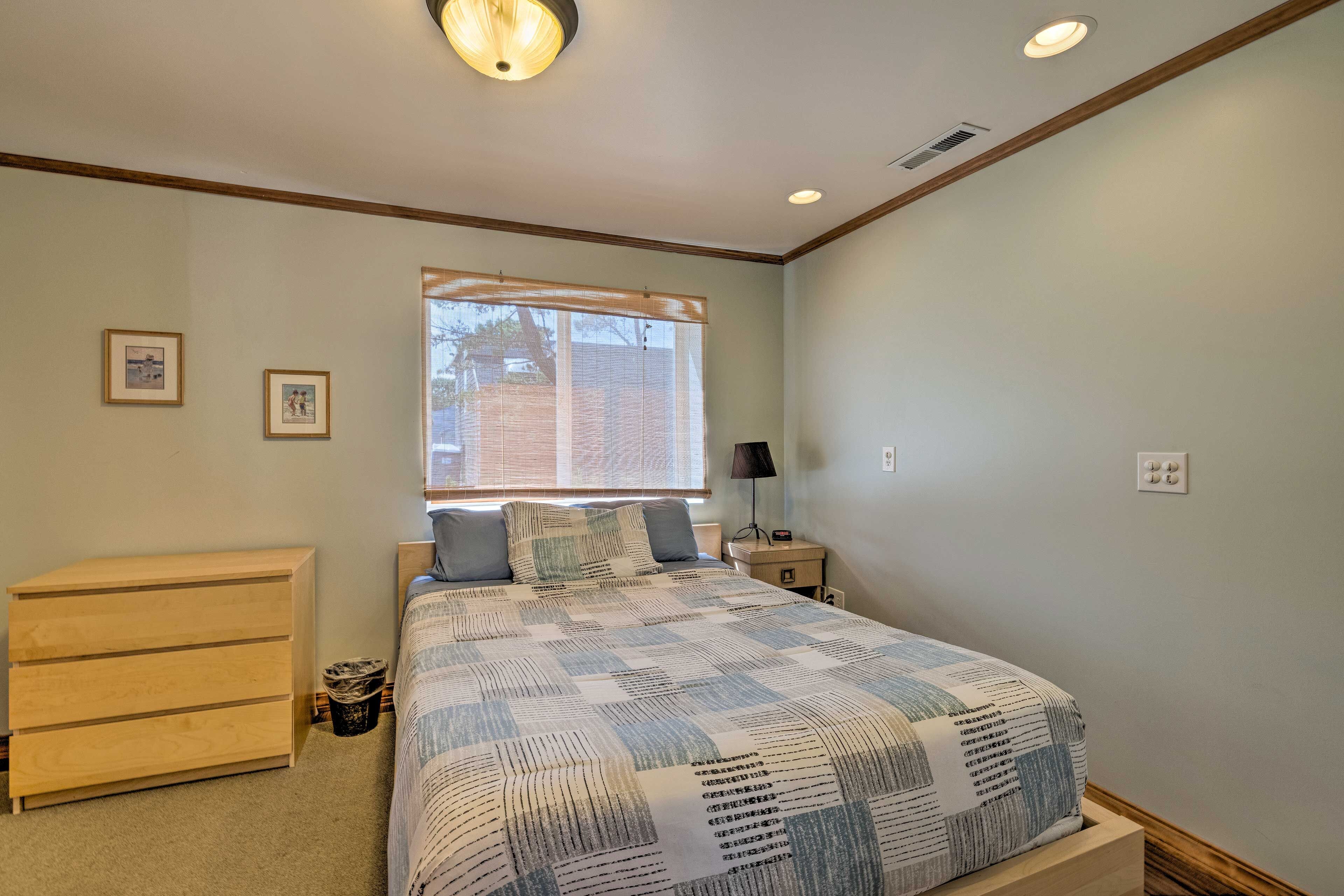 A bedroom with a bed, a dresser, a nightstand, and a window with blinds.