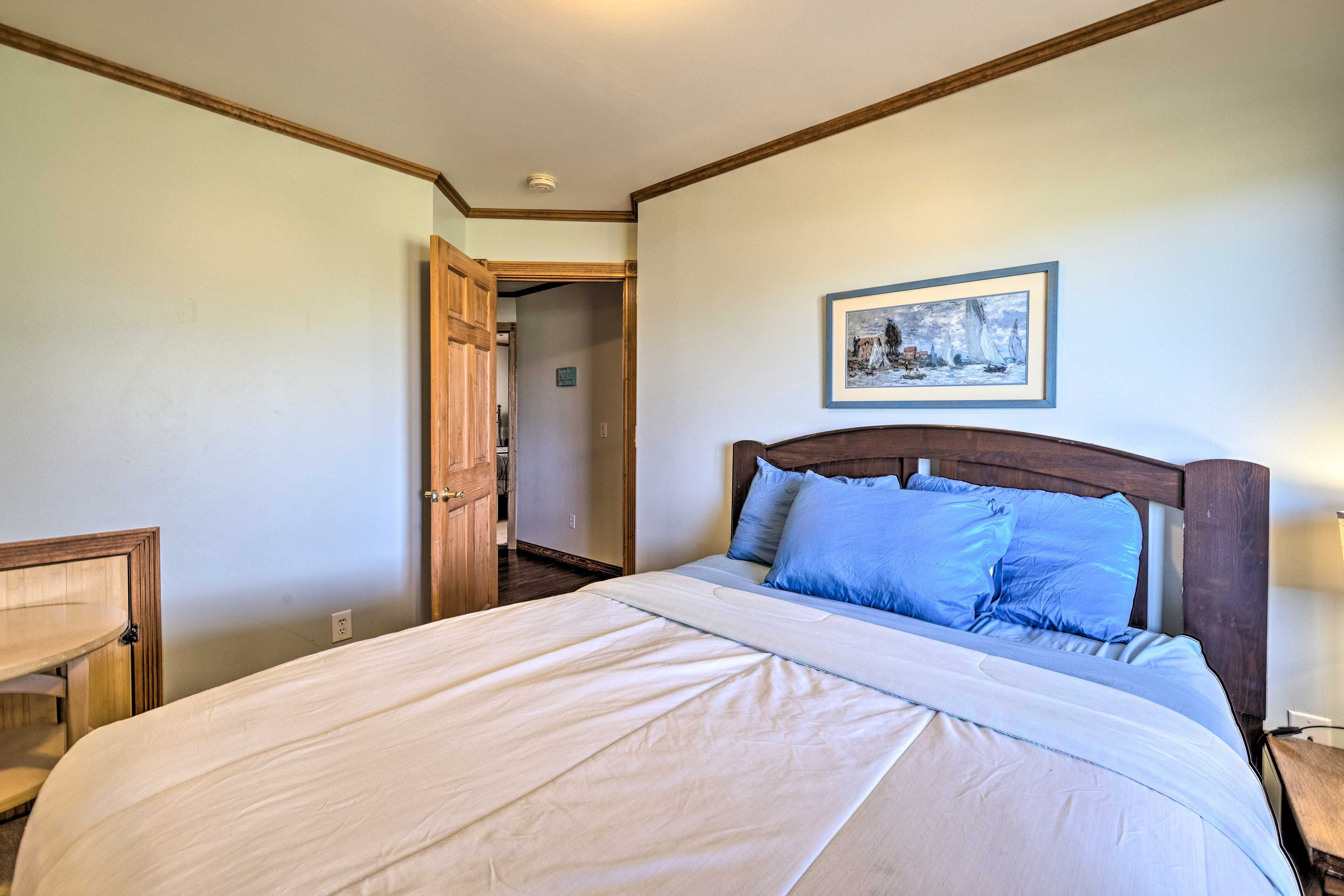 Une chambre d’hôtel avec un grand lit, une tête de lit en bois, une table de chevet et un tableau encadré au mur.