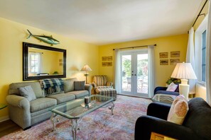 A living room with a sofa, armchair, glass coffee table, and a large mirror. - West Palm Beach Home w/ Fenced-in Yard & Deck! (West Palm Beach)