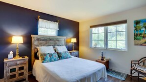 A bedroom with a bed, two bedside tables, a window, and a painting on the wall. - West Palm Beach Home w/ Fenced-in Yard & Deck! (West Palm Beach)