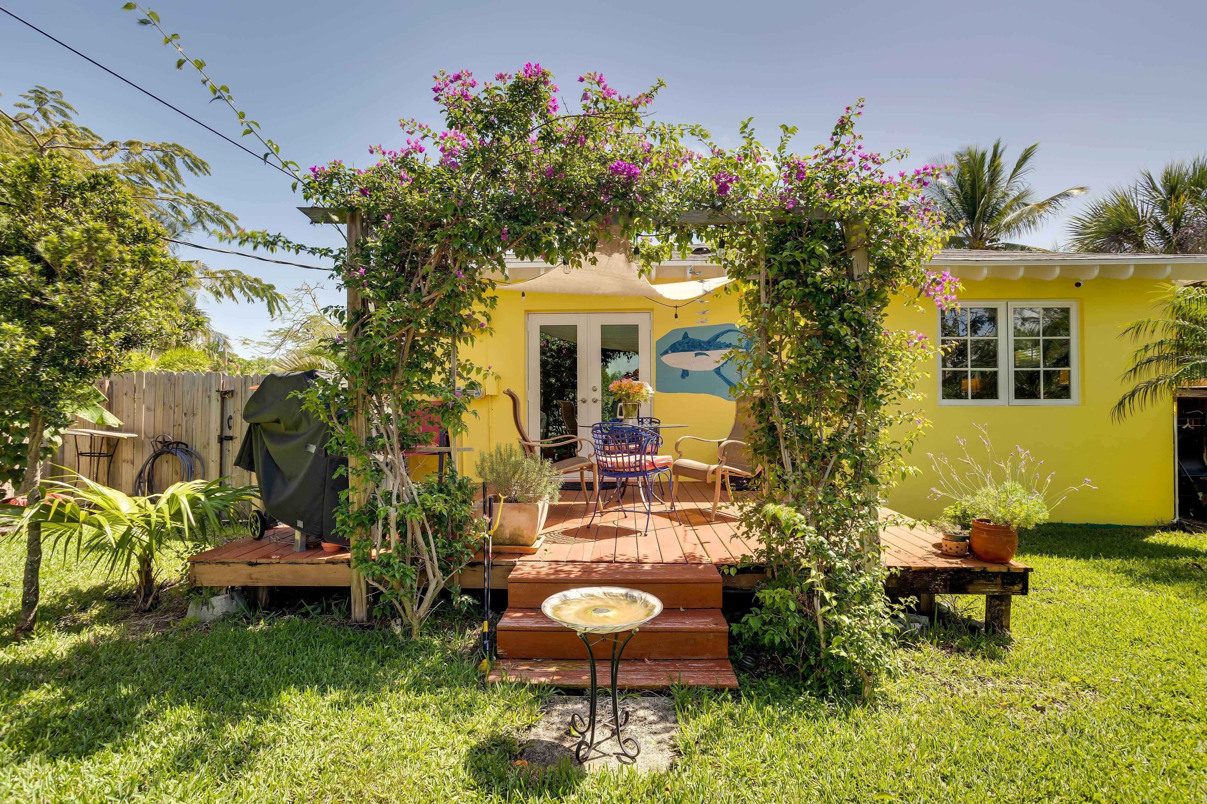 A yellow house with a wooden deck, a patio table, and chairs.