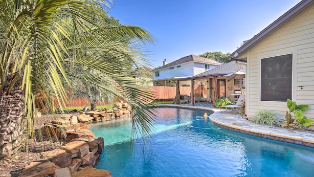 Ein Garten mit Swimmingpool, Palmen und einem Haus.