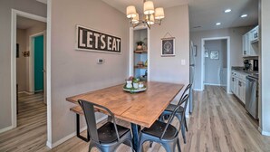 A dining area with a wooden table, black chairs, a chandelier, and a 'LET'S EAT' sign on the wall. - Sunny Family-friendly Branson Home! (Branson)
